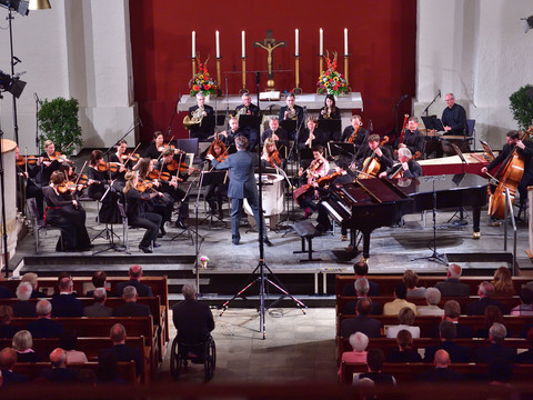 An orchestra performs an opening concert in a concert hall with an audience.