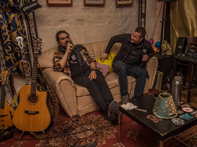 Zwei Künstler sitzen neben Gitarren auf einer Couch in der Kulturlounge Leipzig, Party, Tanzen, Clubs, Feiern.
