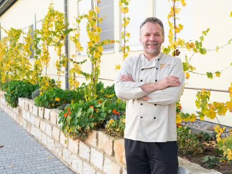 Chocolatier Olav Praetsch - Regional products Chocolatier Olav Praetsch staat met gevouwen armen en een brede glimlach voor zijn Chocolaterie Praetsch Wermsdorf, regionale producten.