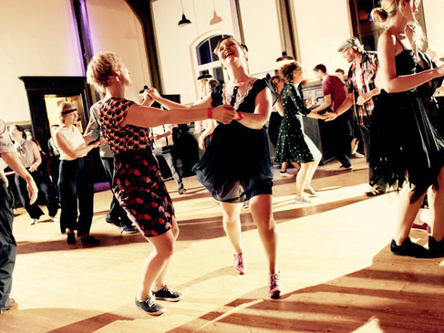 Tanzfreudige Menschen schwingen ausgelassen das Tanzbein zu schwungvoller Musik in einem festlichen Saal.