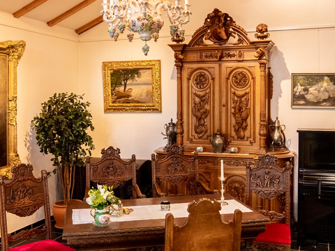 Heimatmuseum Antiker Speisesaal mit Holzstühlen, geschnitztem Schrank und Gemälden an den Wänden.