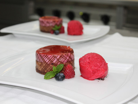 Bergische Genusstage Zwei Teller mit Dessert: Schokoladenmousse-Törtchen und Sorbet, garniert mit frischen Beeren und Minze.