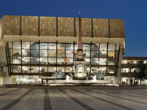 The Gewandhaus in Leipzig illuminated at night, an imposing building with a glass façade.