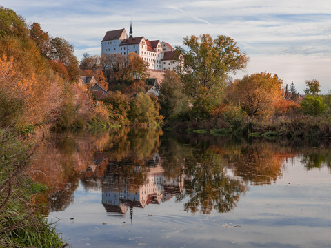 Colditz Castle - Sights in the Leipzig region Colditz Castle, surrounded by colorful trees, reflected in the water, Schlösserland Sachsen, Excursion