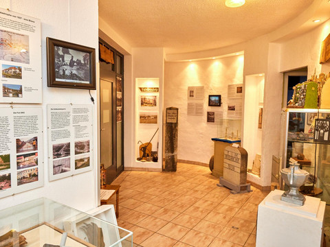 Ein Museumsraum mit Ausstellungsstücken und Informationstafeln über Hochwasserkatastrophen, beleuchtet in warmem Licht.A museum room with exhibits and information boards about flood disasters, illuminated in warm light.Muzejní místnost s exponáty a informačními tabulemi o povodňových katastrofách, osvětlená teplým světlem.Sala muzealna z eksponatami i tablicami informacyjnymi o klęskach powodzi, oświetlona ciepłym światłem.Een museumzaal met tentoonstellingen en informatieborden over overstromingsrampen, verlicht in warm licht.Una sala del museo con esposizioni e pannelli informativi sui disastri dell'alluvione, illuminata da una luce calda.