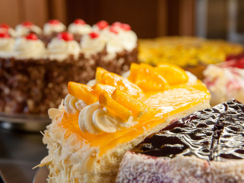 Verschiedene Tortenstücke mit Sahne, Früchten und Schokolade verlocken auf einem Buffet zum Genuss.