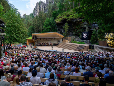 Felsenbühne Rathen Das Freilufttheater namens Felsenbühne Rathen inmitten einer bewaldeten Felslandschaft, gefüllt mit einem großen Publikum, das einer Aufführung auf der Bühne zusieht.