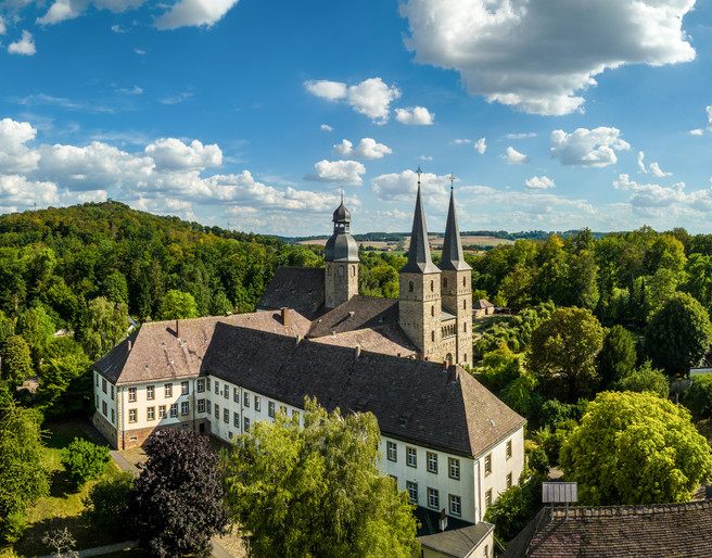 Marienmuenster-Abtei Marienmuenster-Teutoburger-Wald-Tourismus-D-Ketz-075.jpg Luftaufnahme eines historischen Klosters im Grünen, umgeben von dichten Wäldern und Hügeln.