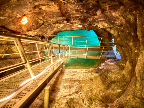 Bij het ondergrondse meer in de bezoekersmijn Unterirdischer See in einem Besucherbergwerk mit beleuchtetem Steg und natürlichem Felsgewölbe.Underground lake in a visitor mine with illuminated footbridge and natural rock vault.Podzemní jezero v návštěvnickém dole s osvětlenou lávkou a přírodní skalní klenbou.Podziemne jezioro w kopalni dla zwiedzających z podświetlaną kładką i naturalnym sklepieniem skalnym.Ondergronds meer in een bezoekersmijn met verlichte loopbrug en natuurlijk rotsgewelf.Lago sotterraneo in una miniera visitabile con passerella illuminata e volta di roccia naturale.