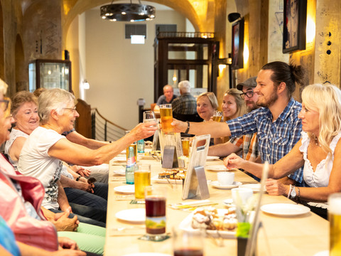 Skupina v restauraci Barthels Hof – volný čas a historie v Lipsku Skupina lidí sedí v kruhu v restauraci Barthels Hof v Lipsku a připíjí si skleničkami.