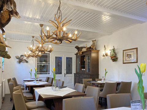 Jagdstübel Gemütliches Restaurant mit Holzmöbeln, Geweihleuchtern und Tierpräparaten an den Wänden; gelbe Tulpen auf den Tischen sorgen für Farbakzente.
