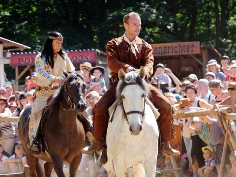 Winnetou-acteurs en ruiters in kostuum tijdens een westernvoorstelling voor publiek.