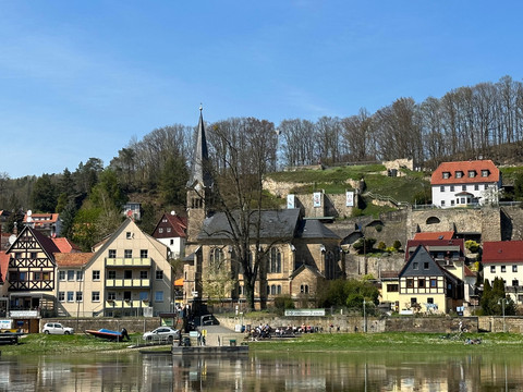 Radfahrerkirche in Wehlen Kleinstadtansicht mit Fachwerkhäusern, Kirche mit hohem Turm und Fluss im Vordergrund, bei klarem Himmel und frühlingshafter Atmosphäre.Small town view with half-timbered houses, church with high tower and river in the foreground, with a clear sky and spring-like atmosphere.Pohled na městečko s hrázděnými domy, kostelem s vysokou věží a řekou v popředí, s jasnou oblohou a jarní atmosférou.Widok małego miasteczka z domami z muru pruskiego, kościołem z wysoką wieżą i rzeką na pierwszym planie, z czystym niebem i wiosenną atmosferą.Stadsgezicht met vakwerkhuizen, kerk met hoge toren en rivier op de voorgrond, met een heldere hemel en lenteachtige sfeer.Veduta di una piccola città con case a graticcio, chiesa con alta torre e fiume in primo piano, con un cielo limpido e un'atmosfera primaverile.