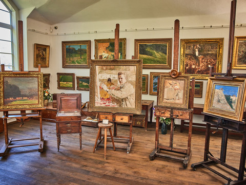 Robert Sterl Haus in Wehlen Ein Atelier mit mehreren Staffeleien, auf denen gerahmte Gemälde stehen; im Hintergrund hängen weitere Bilder an der Wand.
