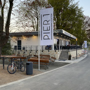 Pier1_Ansicht außen ohne Personen.jpg Flachdachbau mit Gastronomie Pier1 am Weser-Radweg mit Außensitzplätzen