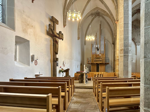 In der Klosterkirche St. Heinrich in Pirna stehen helle Holzbänke unter hohen gotischen Gewölben.