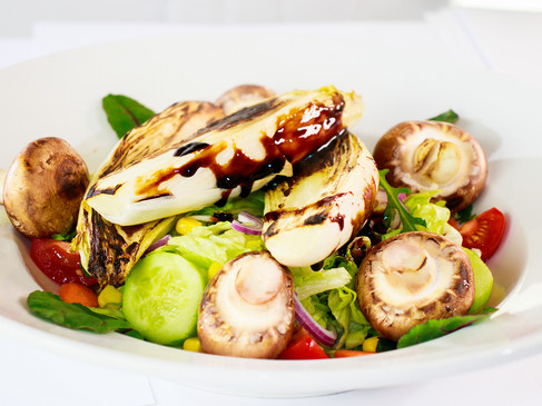 Gegrilltes Gemüse auf frischem Salat, garniert mit Champignons und einem Hauch Balsamico-Creme.