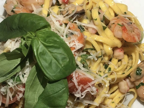 Hausgemachte Pasta mit Garnelen, frischem Basilikum und geriebenem Parmesan, serviert in einem Restaurant.