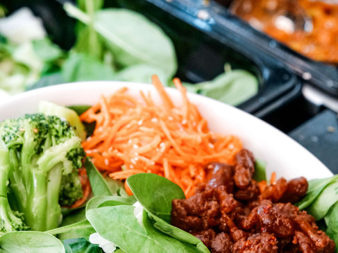 Frischer Salat mit Brokkoli, Karotten und fleischähnlichen Stücken auf einem Buffet präsentiert.