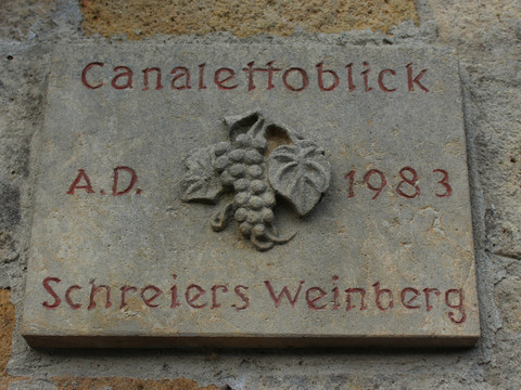 Let op Canaletto uitzicht op het pad Steintafel mit der Inschrift "Canaletto Blick A.D. 1983 Schreiers Weinberg" und einer Reliefdarstellung von Weintrauben und Blättern.