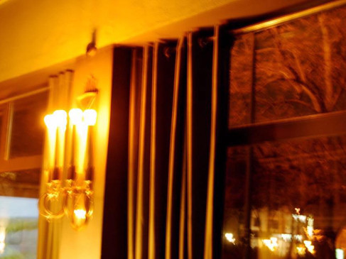 Warme, gedämpfte Beleuchtung in einem Hotelraum, mit Vorhängen und einer großen Fensterfront.