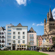 Cologne old town Rhine bank Die Kölner Altstadt am Rheinufer zeigt malerische bunte Häuser und ist von der imposanten Groß St. Martin Kirche überragt, vor strahlend blauem Himmel.Cologne's old town on the banks of the Rhine features picturesque colorful houses and is dominated by the imposing Gross St. Martin Church, set against a bright blue sky.