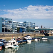 Rheinauhafen Modernes Bürogebäude am Wasser mit Booten im Vordergrund, blauer Himmel und Kölner Dom im Hintergrund.Modern office building on the waterfront with boats in the foreground, blue sky and Cologne Cathedral in the background.