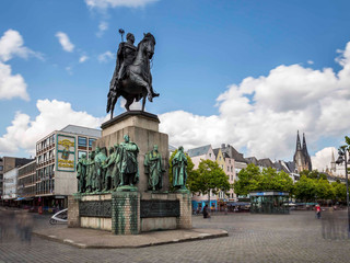 Cologne old town Das Reiterdenkmal am Heumarkt in Köln zeigt eine imposante Darstellung eines Ritters in Rüstung auf einem Pferd, umgeben von einer Gruppe weiterer historischer Figuren. Der historische Stadtkern bildet die beeindruckende Kulisse.The equestrian monument on Heumarkt in Cologne shows an imposing depiction of a knight in armor on a horse, surrounded by a group of other historical figures. The historic city center forms the impressive backdrop.