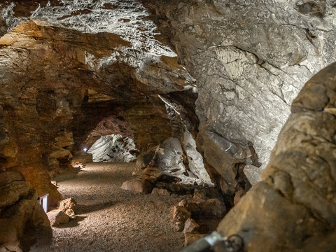 Aggertalhöhle Steinige Höhle mit beleuchtetem, gewundenem Pfad. Wände aus braunen und grauen Felsen mit Textur.