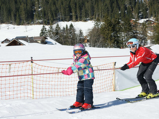 Bientôt, les élèves skieurs prennent presque seuls le téléski à corde Kind lässt sich vom Schlepplift hochziehen, die Skilehrerin ist hinter ihmChild is pulled up by the tow lift, the ski instructor is behind himL'enfant se laisse hisser par le téléski, la monitrice de ski est derrière lui