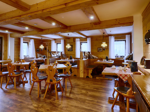 Gezellig, rustiek restaurant met houten meubels, geblokte tafelkleden en warme verlichting; lege tafels en stoelen, uitnodigende sfeer.