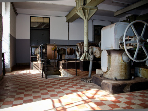 Reuschenberger Mühle Innenansicht Historische Fabrikhalle mit roten Fliesen, alten Maschinen und einem großen Schwungrad.