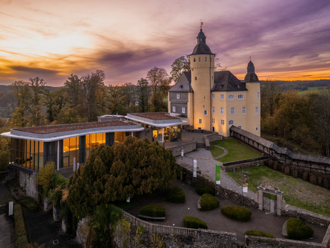 Schloss Homburg Schloss Homburg bei Sonnenuntergang, umgeben von Bäumen und einem modernen Anbau, im Herbst.