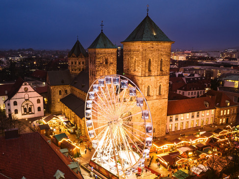 osnabrueck-weihnachtsmarkt-2022-c-max-wiesenbach.jpg Osnabrücker Weihnachtsmarkt bei Abenddämmerung, beleuchtetes Riesenrad vor historischen Gebäuden.Osnabrück Christmas market at dusk, illuminated Ferris wheel in front of historic buildings.Kerstmarkt in Osnabrück in de schemering, verlicht reuzenrad voor historische gebouwen.