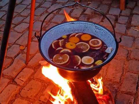 Winterfest in Lieberhausen Kessel mit dampfendem Punsch und Obstscheiben über offenem Feuer auf gepflastertem Boden.