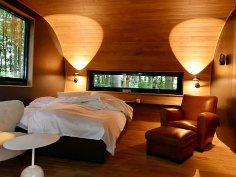 Innenansicht Gemütlich eingerichtetes Schlafzimmer mit Doppelbett, braunem Ledersessel und großer Fensterfront.
