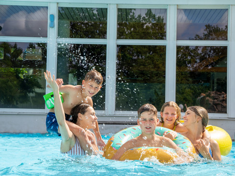 Spielende Kinder im RIFF Bad Lausick - Freizeitbad in der Leipzig Region Fünf Kinder mit Schwimmreifen spielen im Außenbecken des Freizeitbades RIFF in Bad Lausick, Familienausflug, Freizeit, Badespaß