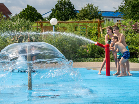 Spielende Kinder im RIFF Bad Lausick - Freizeitbad in der Leipzig Region Drei Kinder spielen am Outdoor-Wasserspielplatz des Freizeitbades RIFF in Bad Lausick mit Wasserkanonen, Familienausflug, Freizeit, Badespaß