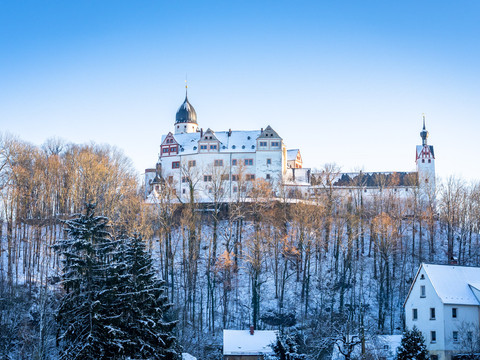 Schloss Rochsburg im Winter - Schlösser der Leipzig Region Blick auf das verschneite Schloss Rochsburg auf einem Felssporn, umgeben von kahlen Bäumen zur untergehenden Sonne, Ausflugsziel