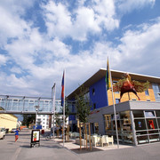 Bielefeld03.jpg Modernes Museumsgebäude mit blauer Fassade, Glassteg und großer Skulptur davor unter blauem Himmel.