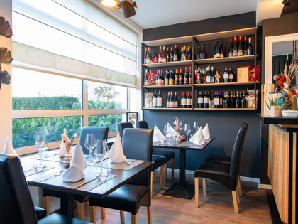 Duo-Terre-Tische.jpg Mit Stoffservietten eingedeckte Tische, an der wand ein Regal mit diversen Weinflaschen