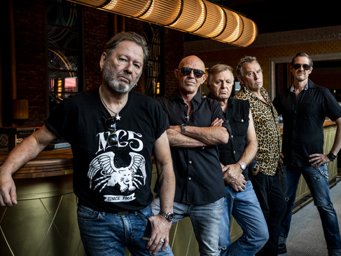 Extrabreit Die Band Extrabreit steht lässig in einer Bar, umgeben von eleganten Retro-Elementen und warmem Licht.