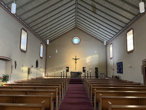 kath. Kirche Wahlscheid <p>Innenansicht einer Kirche mit Holzbänken, rotem Teppich und beleuchtetem Altar mit Kruzifix.</p>