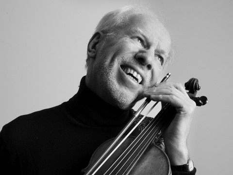 Gidon Kremer (c) Angie Kremer.jpg Gidon Kremer lächelnd mit Violine, schwarz-weiß, humorvoller Ausdruck.