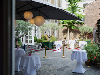 _MG_0013_Bagdu-fuer-Wolkenburg-300dpi_2.jpg Gemütlicher Hofgarten mit Laternen, runden Stehtischen und Pflanzen unter großen Sonnenschirmen.Cozy courtyard garden with lanterns, round bar tables and plants under large parasols.