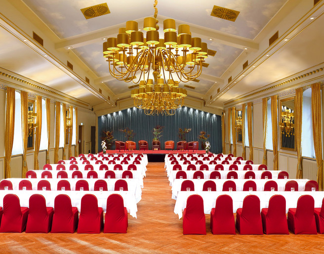 015_festsaal_parlament_blau.jpg Eleganter Ballsaal mit goldenen Kronleuchtern, roten Stuhlbezügen und spiegelverzierten Wänden.Elegant ballroom with golden chandeliers, red chair covers and mirrored walls.