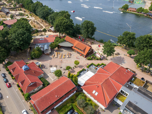alfsee-drone(c)tol-foto-jurjen-drenth (8).JPG Freizeitpark neben einem See, mit roten Dächern und grünem Umfeld aus der Vogelperspektive.