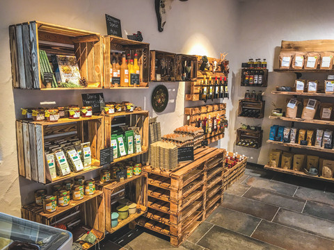 Hofladen innen  Ein gemütlicher Hofladen mit rustikalen Holzregalen, gefüllt mit regionalen Produkten und Delikatessen.