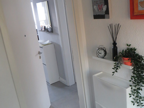 IMG_3831.JPG Moderner Eingangsbereich in einem Gebäude mit heller Tür, dekorativen Bildern und Pflanzen.