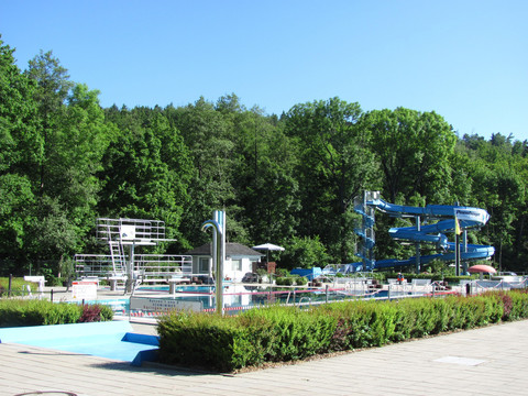Freibad Berggießhübel / Copyright Stadt BGB.jpg Freibad Berggießhübel mit Rutschen und Sprungturm, eingebettet in grüne Waldkulisse unter blauem Himmel.